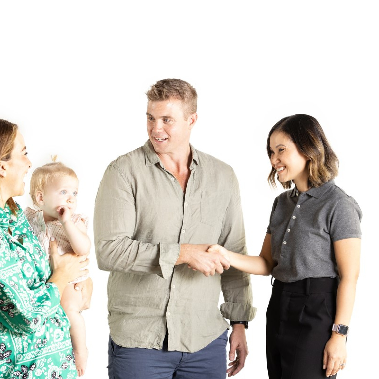 A couple with a baby shake hands with a woman in a grey polo shirt