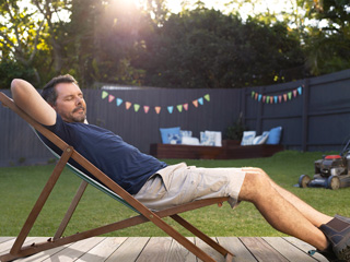 A man relaxes on a deck in a lawn chair